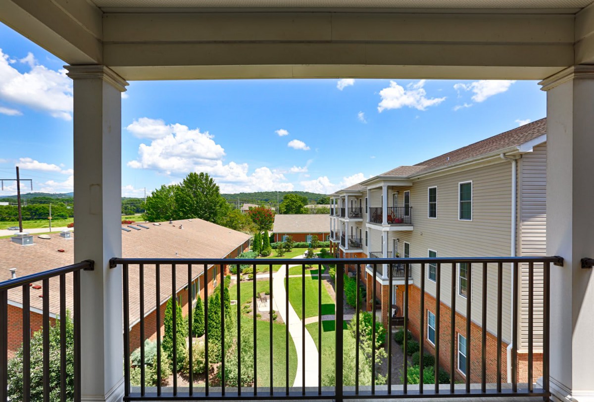 View from a balcony overlooking an apartment complex courtyard on a sunny day.