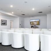 A modern conference room with white seating and a projector screen.