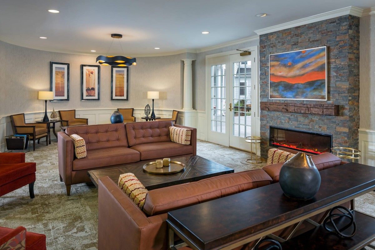 A stylish and cozy living room featuring a sofa, coffee table, and a fireplace adorned with artwork.