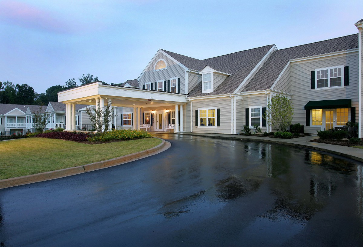 A large residential home with a covered entrance and a curved driveway.