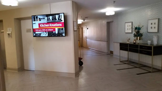 A hallway with a television displaying an advertisement for Kitchen Kreations Cafe & Catering.