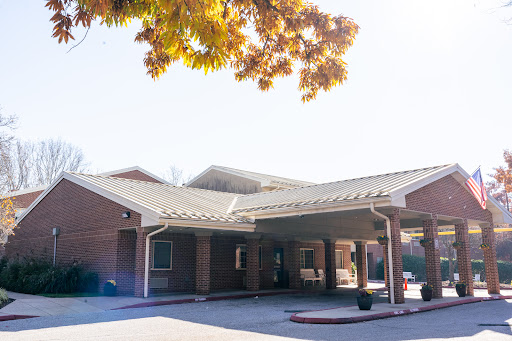 A welcoming entrance of a modern red brick building, surrounded by trees on a sunny day.