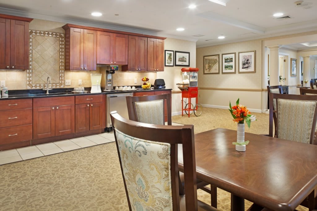 A cozy kitchen and dining area featuring wooden cabinets, a countertop, and a vase with flowers on the table.