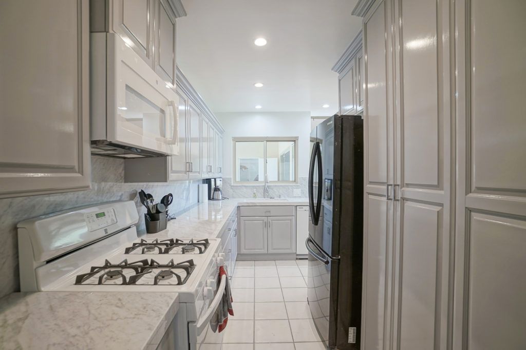 A modern kitchen with white cabinetry and a stainless steel refrigerator.