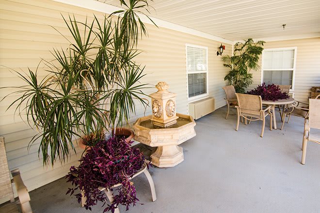 A cozy outdoor patio with lush plants, a decorative fountain, and seating area.