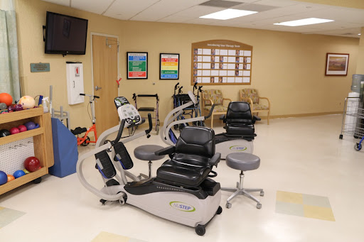 A well-equipped rehabilitation room featuring various exercise machines and seating arrangements for patients.