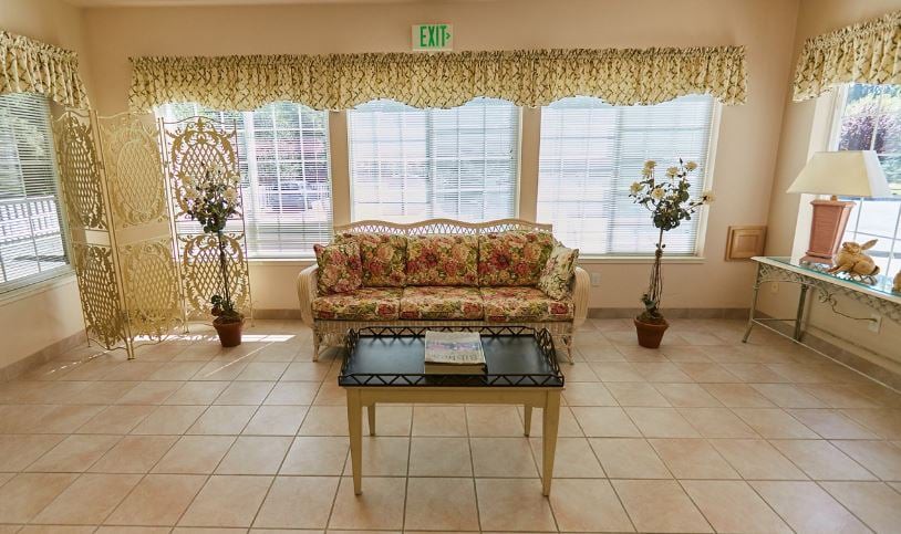 A cozy living room with floral furniture and large windows.