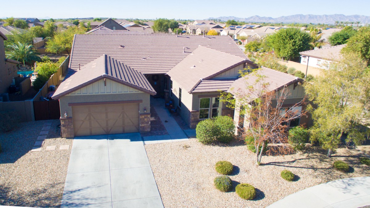 Aerial view of a suburban house with landscaped front yard and driveway.