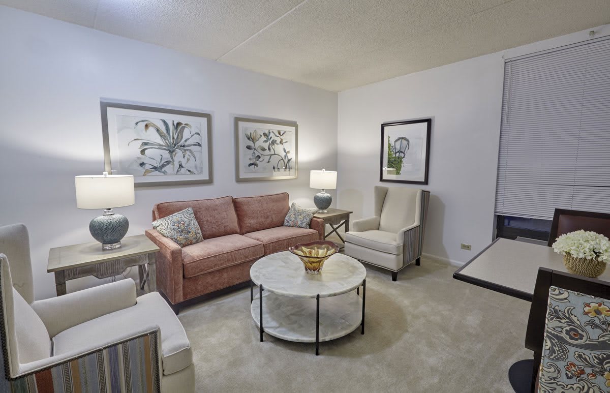 A cozy living room with a pink sofa, armchairs, and tasteful artwork on the walls.