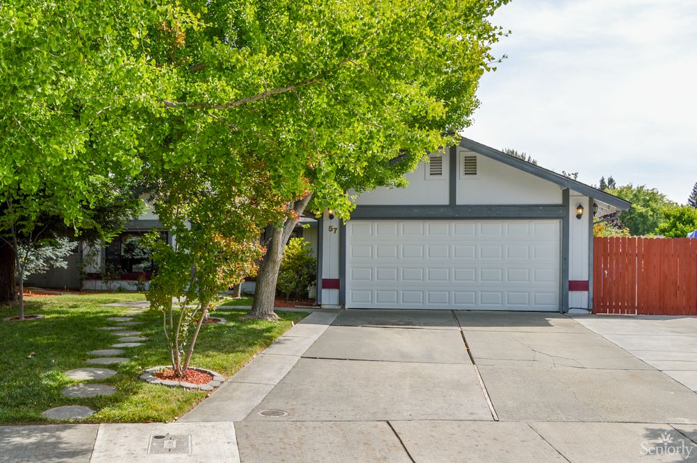 A suburban house with a double garage and a tree-lined driveway.