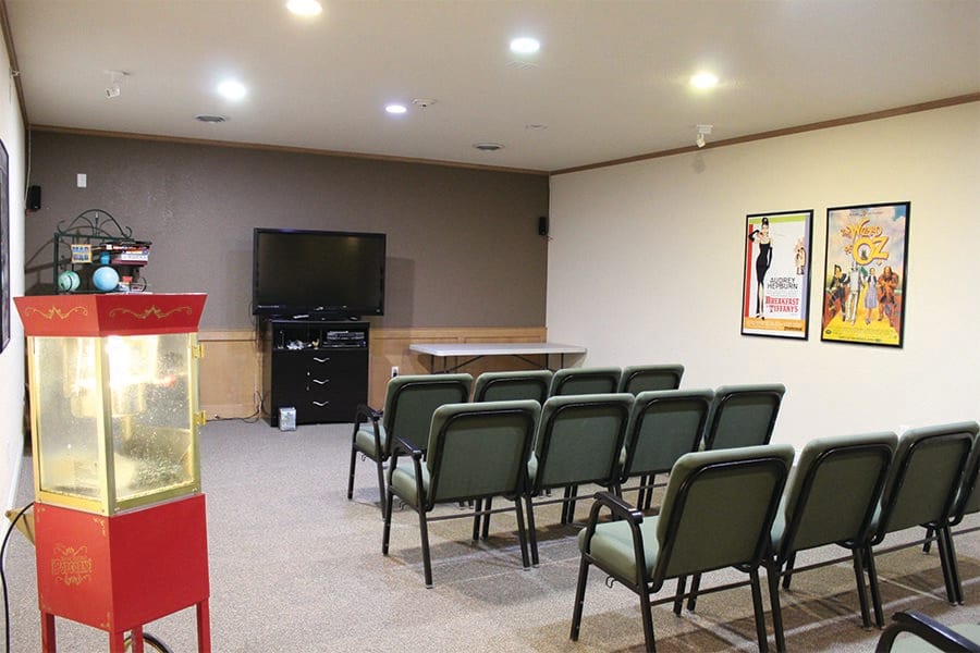 A cozy home theater setup with a row of chairs facing a large TV, accompanied by a popcorn machine.