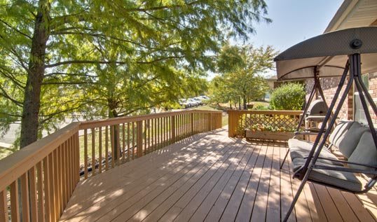 A sunny outdoor wooden deck surrounded by trees.