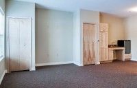 An empty room with carpet flooring and two doors.