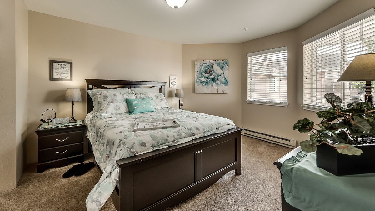 A cozy bedroom with a neatly made bed, featuring floral bedding and a matching artwork on the wall.