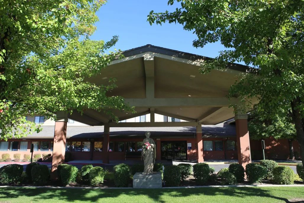 A modern architectural building surrounded by lush green trees.