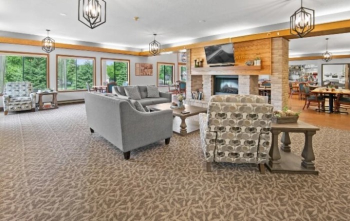 A cozy living room with comfortable seating, a fireplace, and large windows offering natural light.