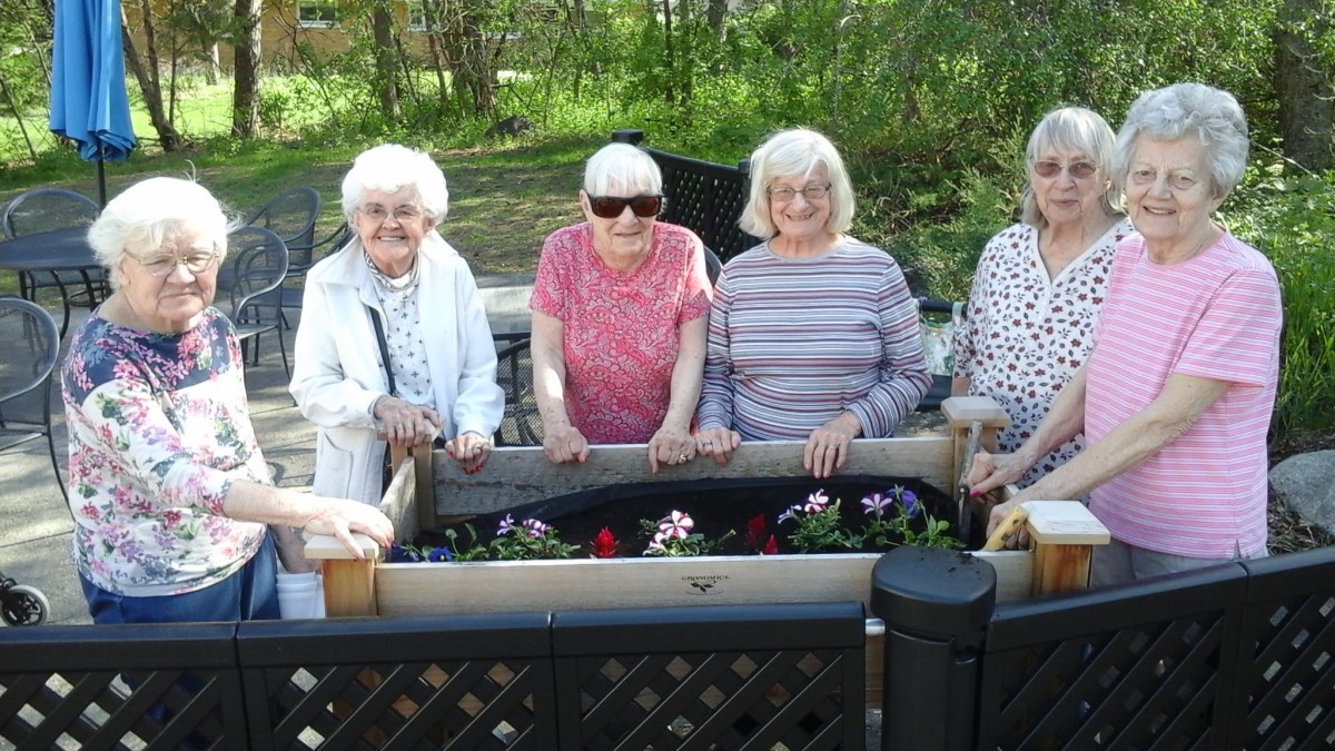 A group of elderly women enjoying gardening together outside.