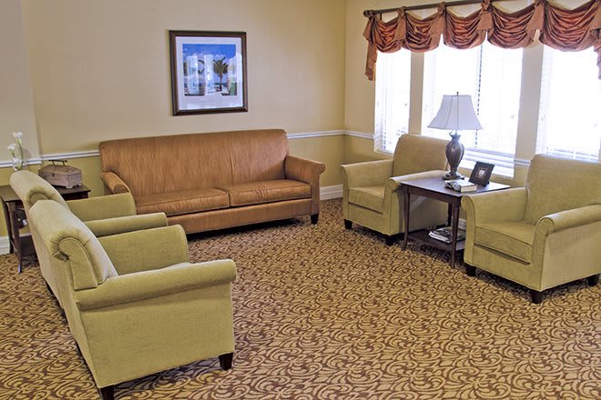 A cozy living room with a sofa, armchairs, and a table under a window.