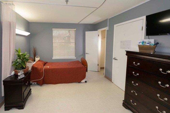 A neatly arranged bedroom with a single bed, dresser, and a window.