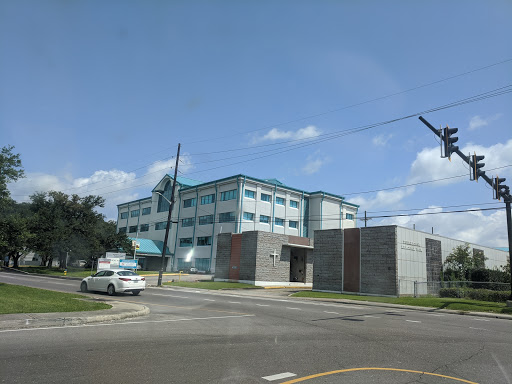 A modern building situated at the corner of a street, with a clear blue sky in the background.