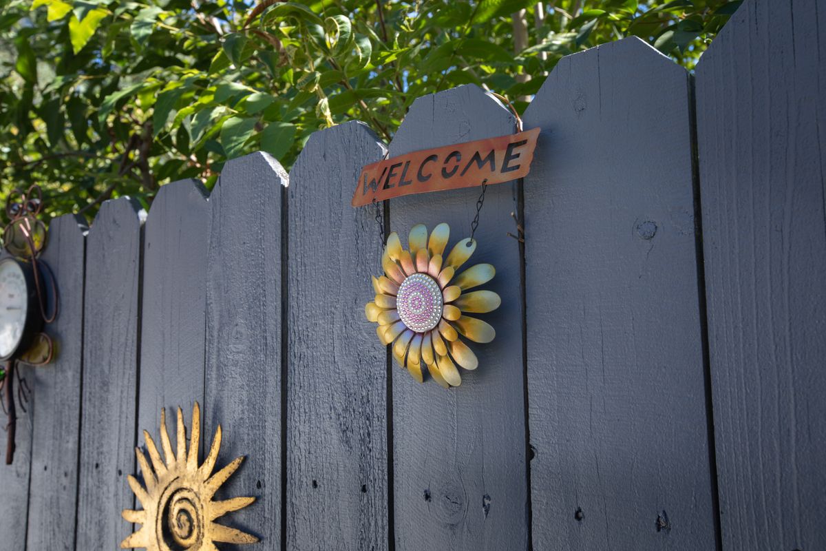 A welcoming fence decorated with a sunflower and sun motif.