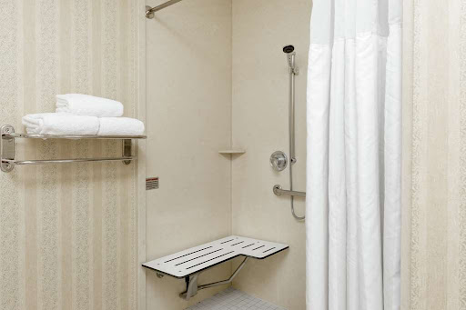 A clean and accessible shower area equipped with a folding bench and neatly arranged towels.