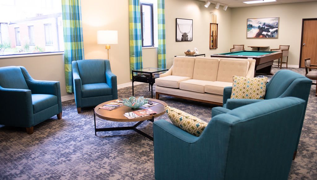 A cozy living room with blue chairs and a beige sofa arranged around a wooden coffee table.