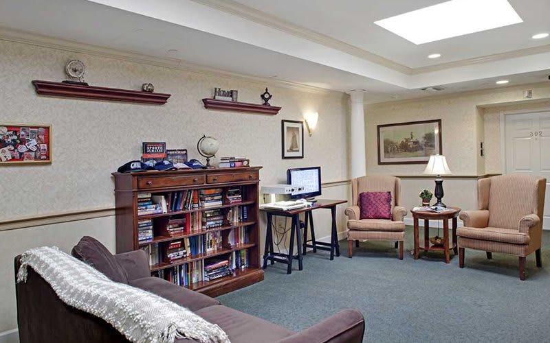 A cozy living room with a computer desk, bookshelf, and comfortable seating.