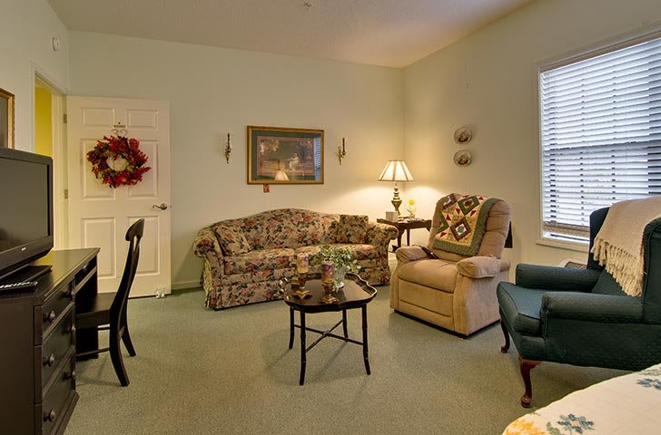 A cozy living room featuring a floral sofa, armchair, and warm lighting.