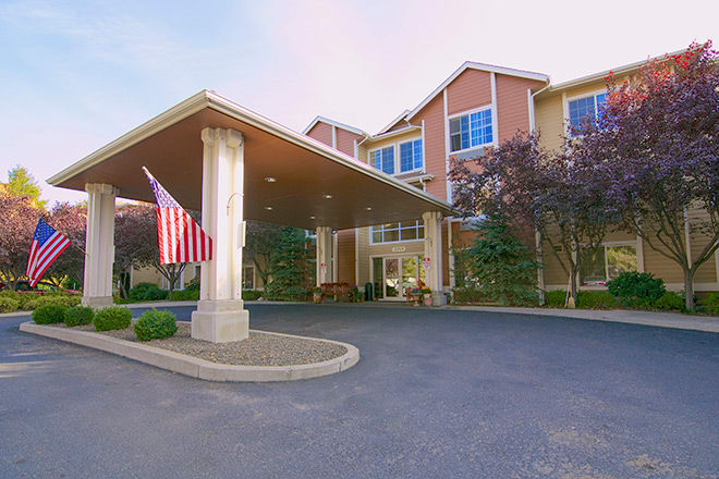 Exterior view of a building entrance with an American flag and surrounding trees.