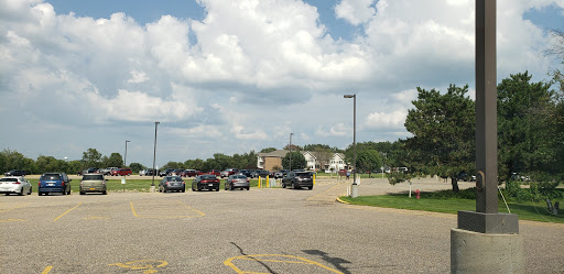 A view of a parking lot with several cars under a partly cloudy sky.