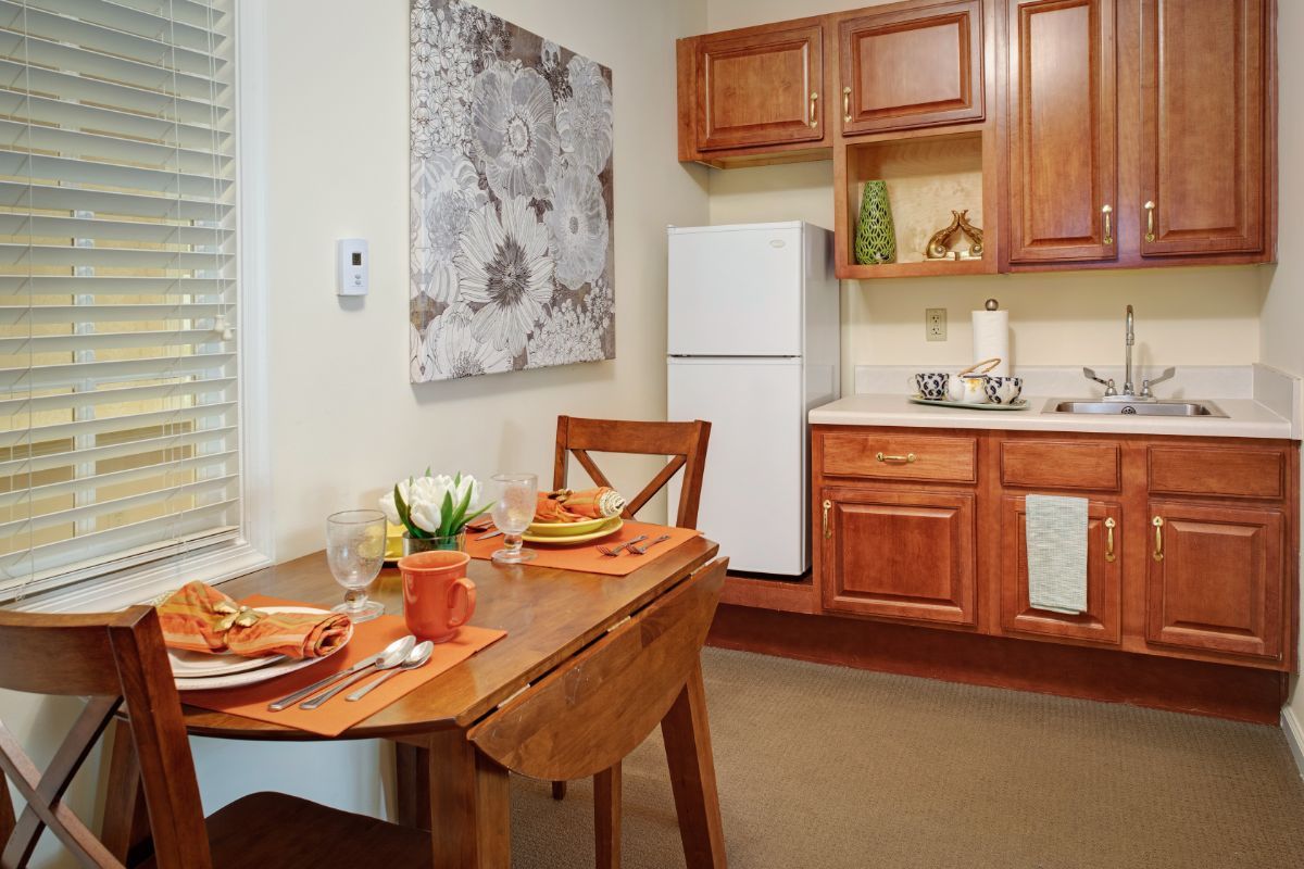 A cozy kitchen and dining area with wooden cabinets and a neatly set table.