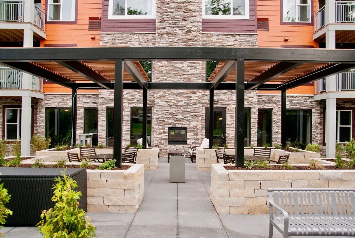 A modern outdoor patio featuring a central fireplace and comfortable seating surrounded by sleek architecture.