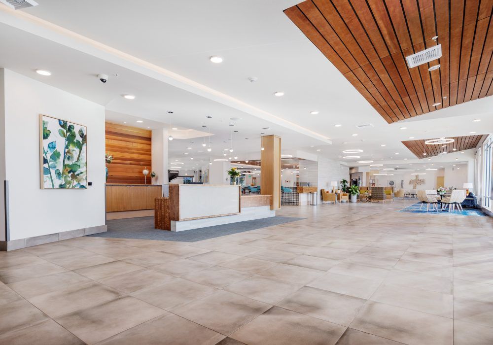 A spacious and modern lobby with a reception desk and seating area, featuring wood accents and bright lighting.