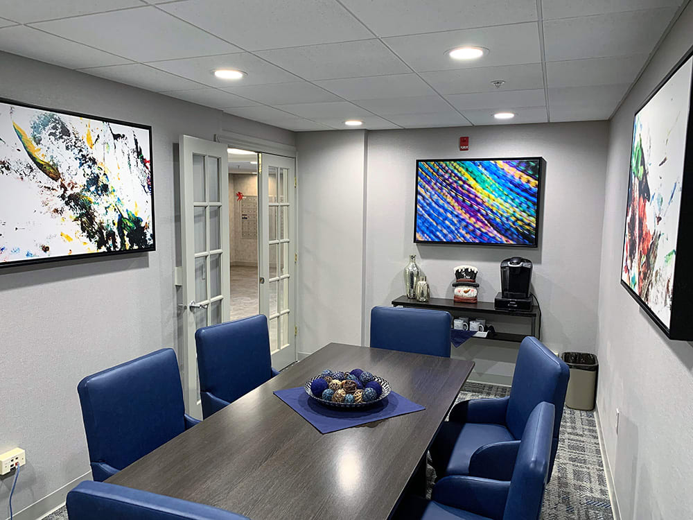 A modern conference room with blue chairs and colorful artwork on the walls.