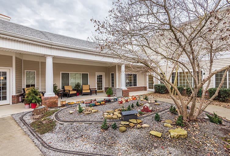 A well-maintained courtyard garden with a pathway, outdoor seating, and landscaping in front of a building.
