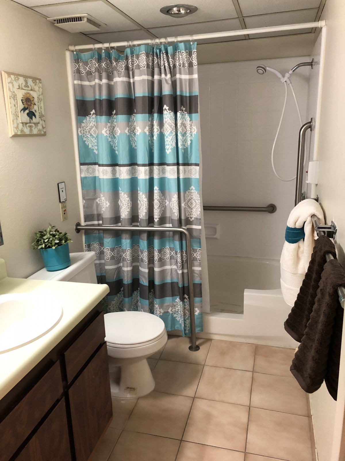 A well-organized bathroom with a shower, toilet, and sink, featuring a striped shower curtain and towels.