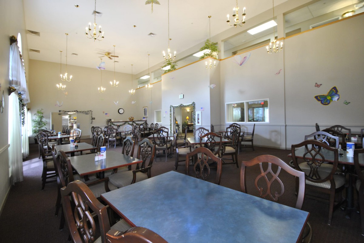 An empty dining room with neatly arranged tables and chairs under bright lighting.
