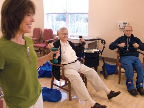 A group exercise session for seniors, focusing on strength training with dumbbells.