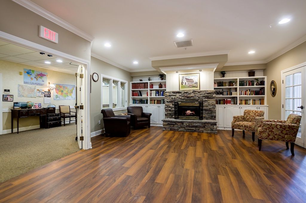 A cozy living room with a central fireplace, surrounded by bookshelves and comfortable seating.