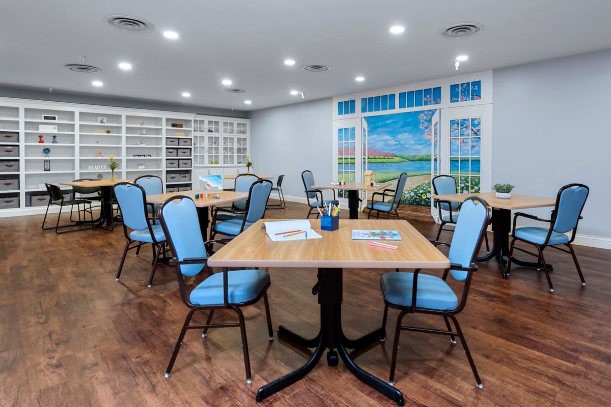 A cozy library reading room with tables and chairs surrounded by bookshelves.