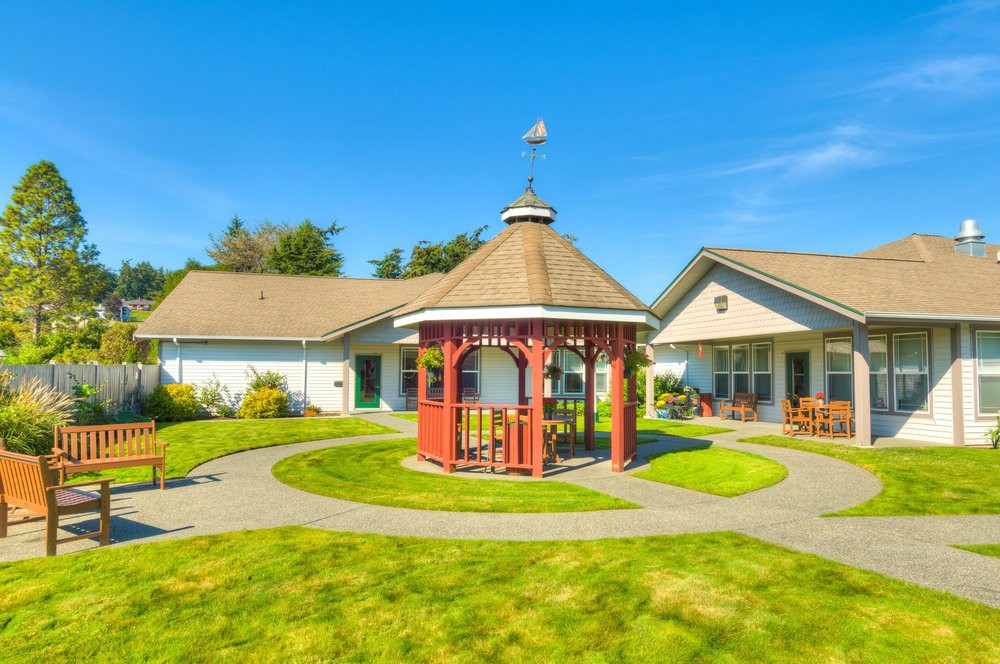 A charming gazebo surrounded by a well-maintained garden with clear blue skies overhead.