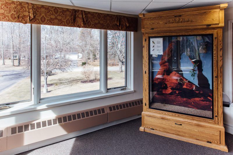 A museum exhibit featuring a wooden display case near a sunlit window.