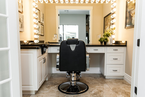 A stylish beauty vanity setup complete with bright lighting and a comfortable black chair.