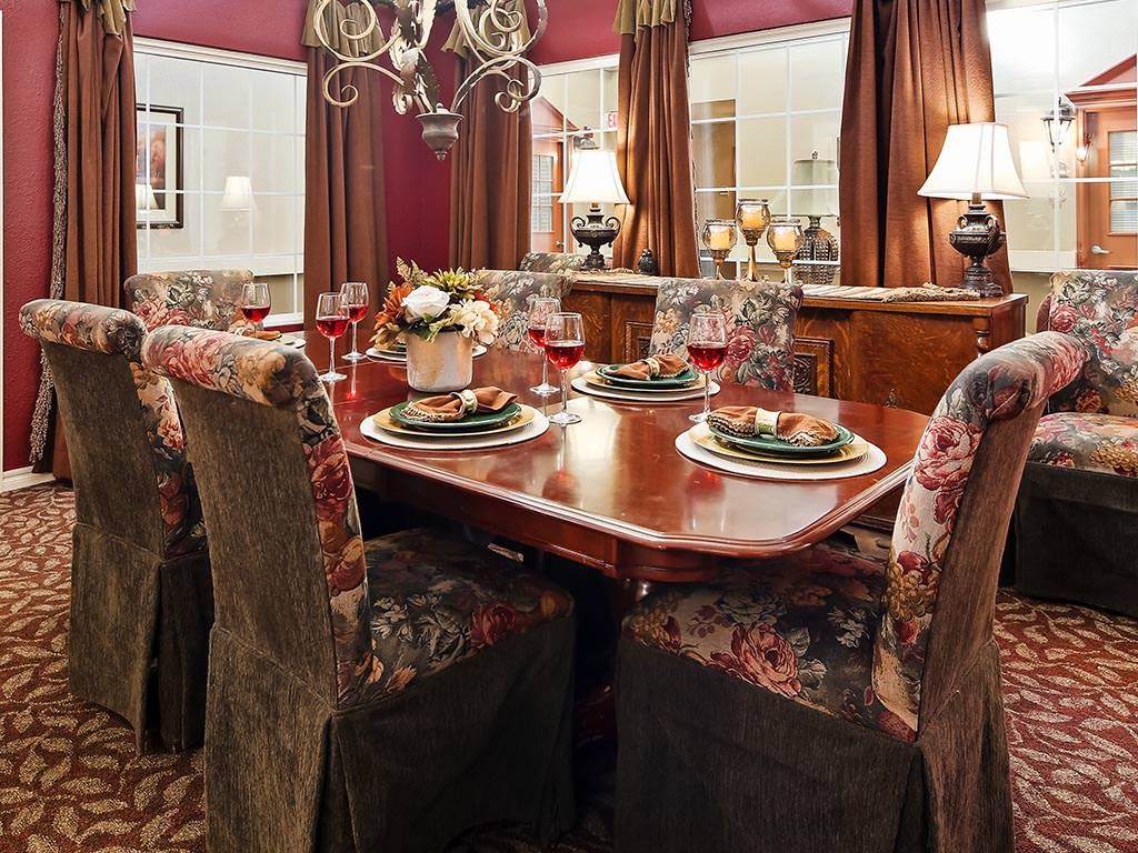 An elegantly decorated dining room with a polished wooden table and floral upholstered chairs.