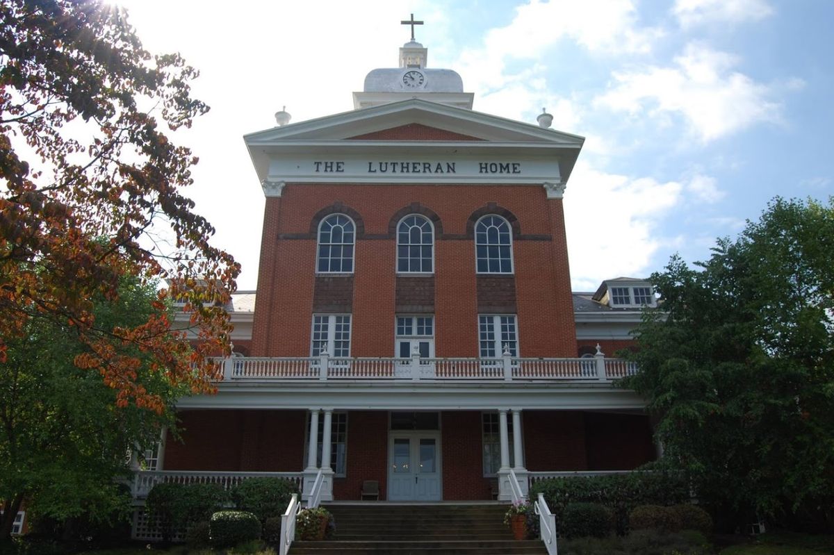 A historic brick church building with a prominent front facade and a cross on top.