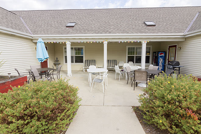 A cozy outdoor patio with tables and chairs under a porch.