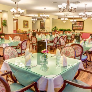 A cozy restaurant dining area with elegantly set tables and classic chandeliers.