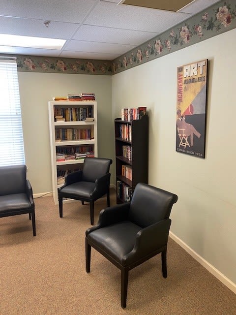 A cozy office space with bookshelves and comfortable chairs.
