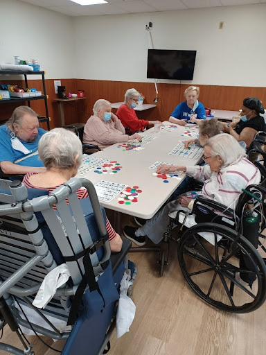 A group of elderly individuals engaging in a game at a community center, showcasing social interaction and activity.
